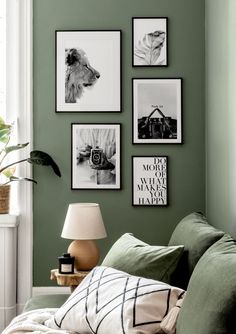 a living room with green walls and pictures on the wall above the couch, along with a lamp