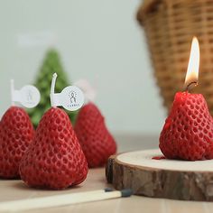 some strawberries are sitting on a table next to a small candle with a stick sticking out of it