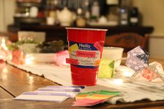 a red cup sitting on top of a wooden table next to paper and other items