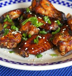 chicken wings with sesame seeds and garnishes on a blue and white plate