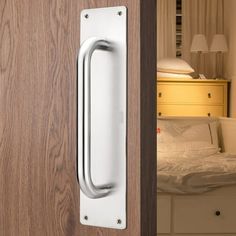 a door handle on a wooden door in a room with a white bed and dresser