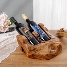 three bottles of wine sitting in a wooden holder on a table next to a lace doily