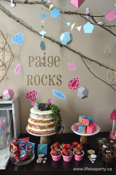 a table topped with cakes and desserts next to a wall