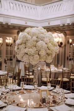 an elegant centerpiece with white flowers is displayed on a round table in the ballroom