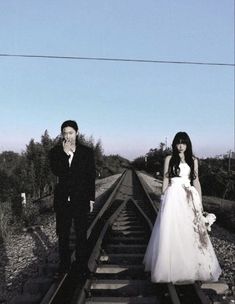 a man and woman standing on train tracks