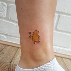 a small teddy bear tattoo on the ankle