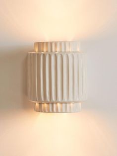 a white wall light mounted on the side of a wall