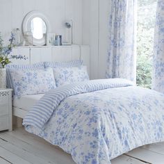 a bedroom with white walls and blue flowers on the comforter, bedding and curtains