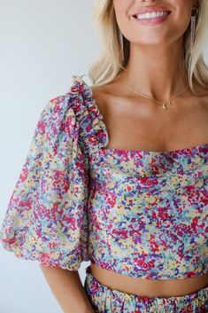 Need a little something to sweeten up your closet? We recommend the Instantly Perfect Multicolored Floral Cropped Blouse! This eye-catching blouse is designed to add a playful and vibrant touch to your everyday outfits, blending a lively floral print with a modern cropped silhouette. Crafted from lightweight, breathable fabric, this blouse features a rich multicolored floral pattern that exudes a fresh and summery vibe. The cropped design offers a flattering fit that pairs effortlessly with high Playful Summer Blouse With Ruffles, Playful Ruffled Blouse For Summer, Playful Fitted Tops For Day Out, Playful Floral Print Blouse For Spring, Spring Multicolor Square Neck Tops, Multicolor Square Neck Tops For Spring, Summer Puff Sleeve Blouse For Garden Party, Chic Pink Top For Garden Party, Playful Spring Printed Blouse