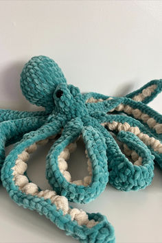 an octopus made out of yarn sitting on top of a white table next to a stuffed animal