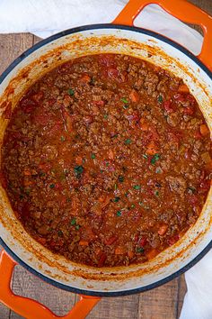 a large pot filled with chili on top of a wooden table next to an orange spatula