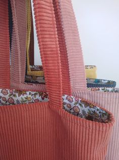 an orange purse hanging from the ceiling in front of a mirror with pink pleated fabric