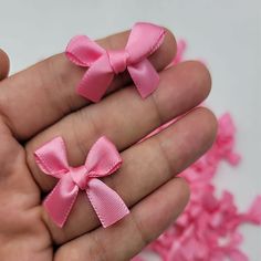 two small pink bows in the palm of someone's hand