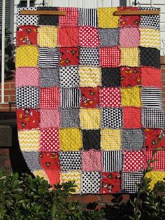 a patchwork quilt hanging on the side of a house