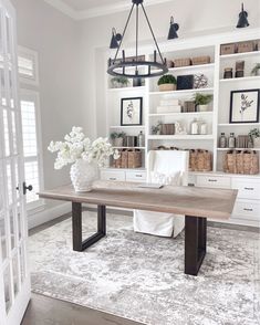 a large wooden table sitting in front of a white book shelf filled with lots of books