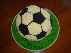 a soccer ball cake sitting on top of a green and white plate covered in frosting