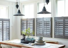 a dining room table with plates on it and three lights hanging over the top of them