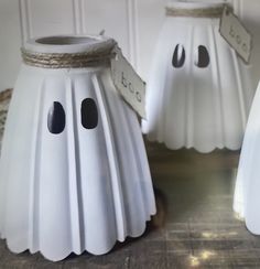 three white plastic ghost candlesticks with tags on them