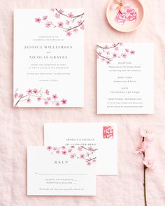 the wedding stationery is laid out on a pink table cloth with flowers in it