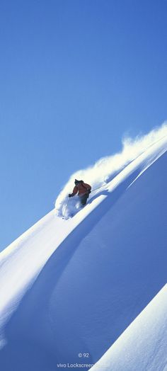 a person riding skis down a snow covered slope in the middle of the day