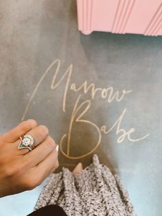 a person holding a diamond ring in front of a chalkboard with the word manor base written on it