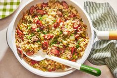 a white bowl filled with rice and vegetables on top of a table next to a green spoon