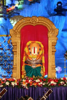 an idol sitting on top of a stage surrounded by flowers