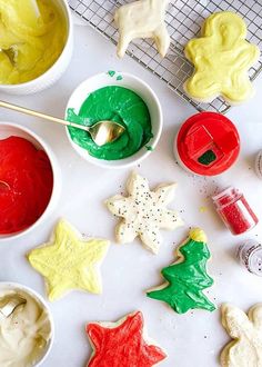 decorated cookies and icing in bowls on a cooling rack