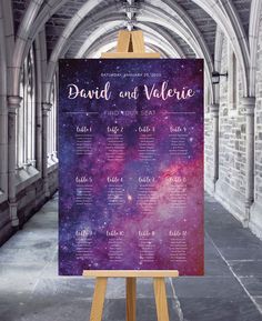 a purple and blue space themed wedding seating plan on an easel in a building