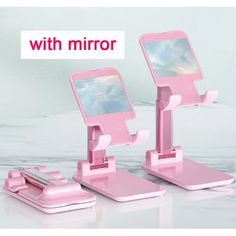 two pink cell phones with mirrors attached to each other on top of a white table