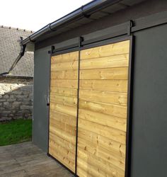 a large wooden garage door on the side of a building with grass in the background