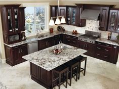 a kitchen with marble counter tops and dark wood cabinets