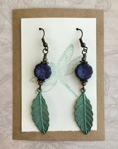 I paired dark blue Czech glass flowers with green patina leaves. Simple and elegant, these earrings are perfect for any time of the year and are easy to wear with almost anything. The earring hooks are antique brass and are nickel free. Lever back hooks are available upon request. All of my earrings come on a hand stamped earring card and are lovingly wrapped in colorful tissue and placed in a drawstring bag, ready to give as a gift. I mail them in a bubble envelope for extra protection. Thank y Blue Nature-inspired Drop Earrings, Nature-inspired Blue Dangle Earrings, Women Nature, Patina Earrings, Stamped Earrings, Casual Earrings, Green Patina, Earring Card, Earrings Antique