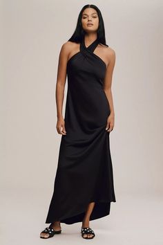 a woman is wearing a black dress with an asymmetrical halter and sandals