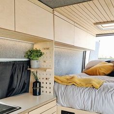 a small bedroom with a bed, desk and stove top oven in the corner next to an open window