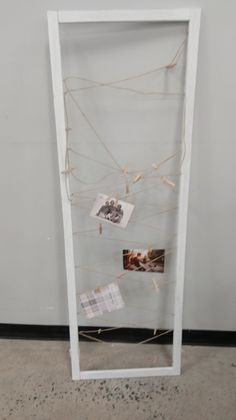 a white frame with pictures hanging on it and some string attached to the front wall