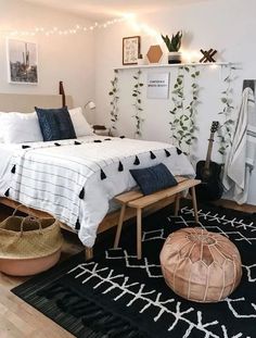 a bedroom with white walls, black and white bedding, wooden flooring and plants on the wall