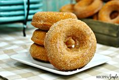 three donuts stacked on top of each other on a white plate with blue napkins in the background