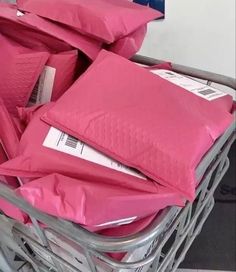 a shopping cart filled with pink bags and envelopes