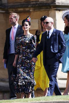 the couple are holding hands as they walk down the street with other people behind them