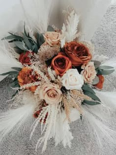 an arrangement of flowers and feathers is displayed on the floor in front of a white wall