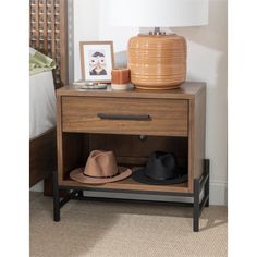 a nightstand with hats on it next to a lamp