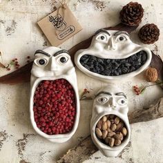 three ceramic bowls filled with fruit and nuts in the shape of people's faces