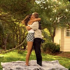 a man and woman embracing on a blanket in the grass