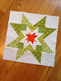 a green and white quilted star sitting on top of a wooden floor