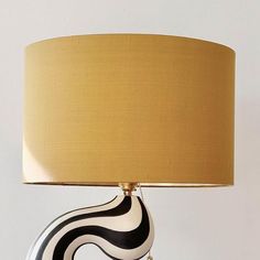 a black and white table lamp with a gold shade on it's base, against a white wall