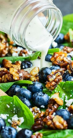 blueberries, walnuts, and spinach are mixed together in a salad dressing