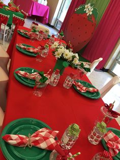 the table is set with red and green plates, napkins, and candy canes