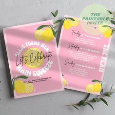 two pink and yellow lemons are on top of the wedding stationery, with greenery