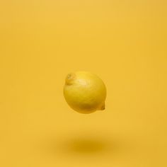 an orange is flying through the air on a yellow background with no one around it